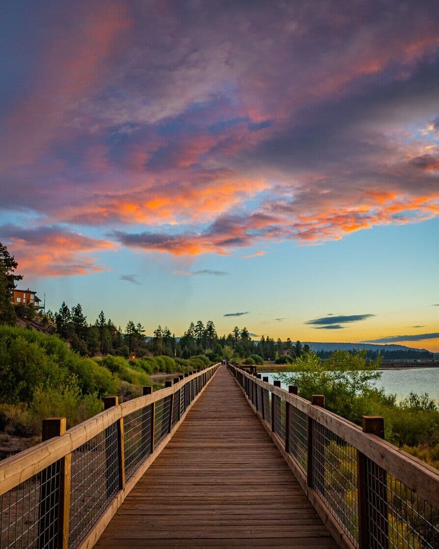 Wooden lakeside boardwalk under a colorful sunset