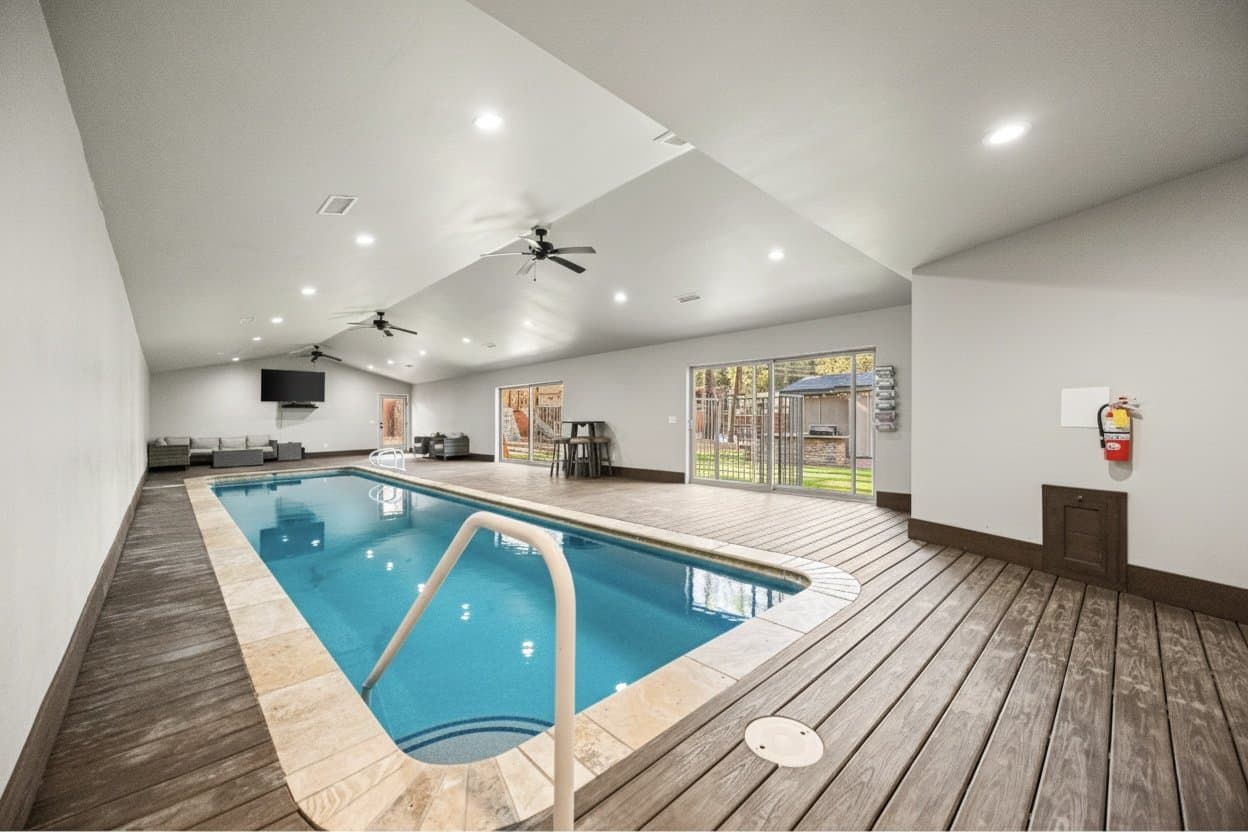 Indoor pool at an Ikoi home, with a wood deck, vaulted ceiling, and lounge area
